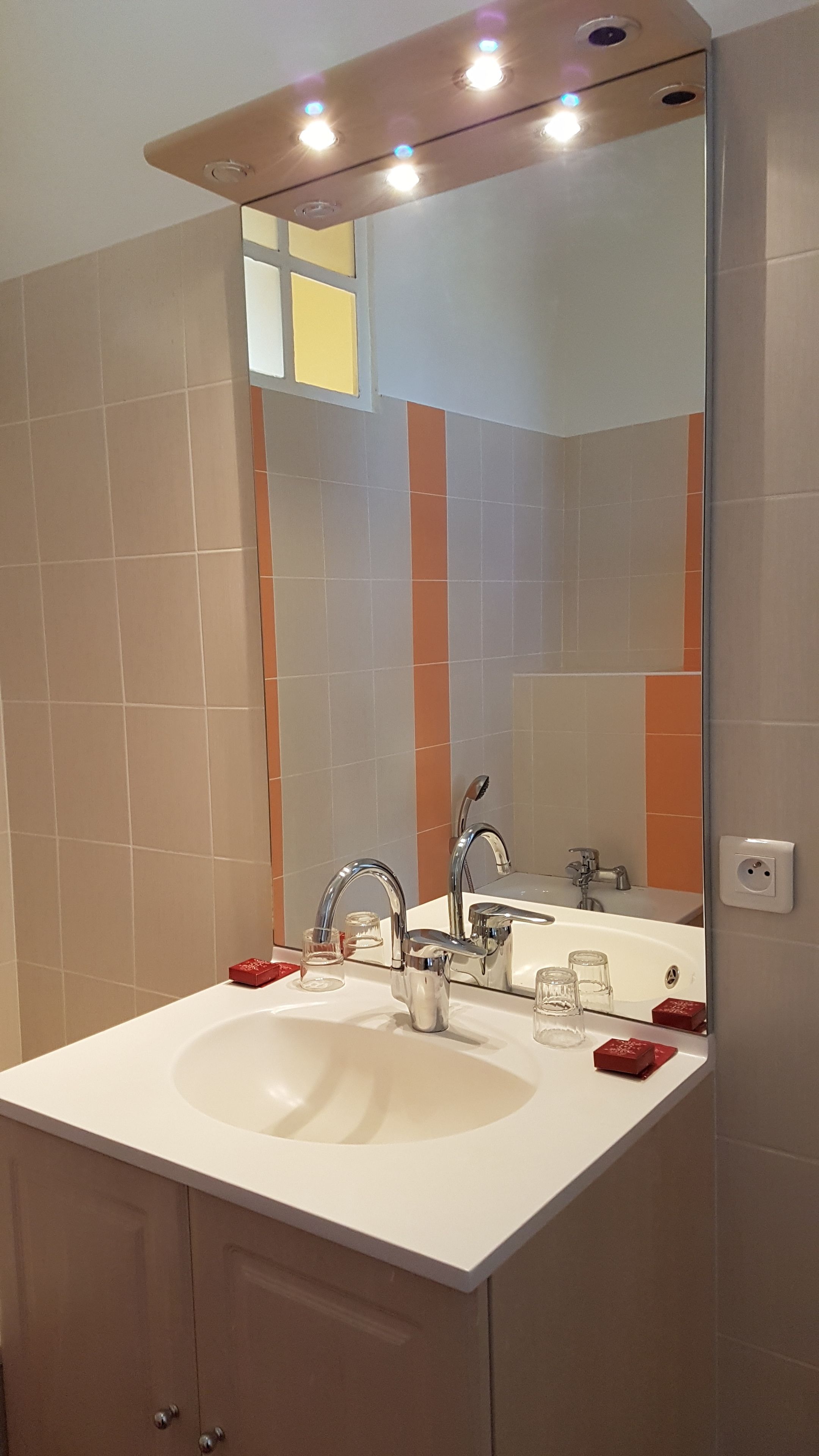 A bathroom with a white sink, two faucets, and a large mirror.