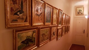 A hallway with a series of framed artworks on the wall, leading to a door. - Hôtel Cardinal (Aix-en-Provence)
