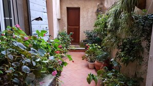 A narrow courtyard with potted plants and a wooden door. - Hôtel Cardinal (Aix-en-Provence)