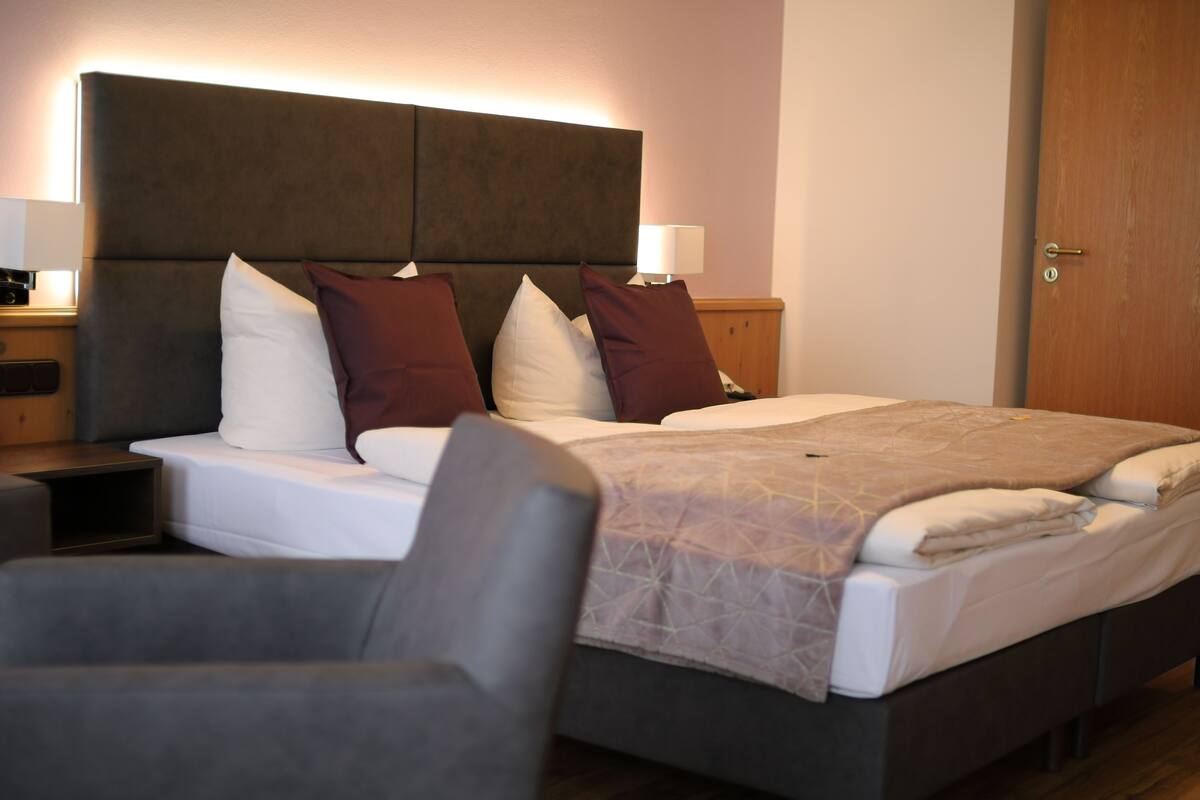 Een hotelkamer met een groot bed, een hoofdbord, nachtkastjes en een stoel.