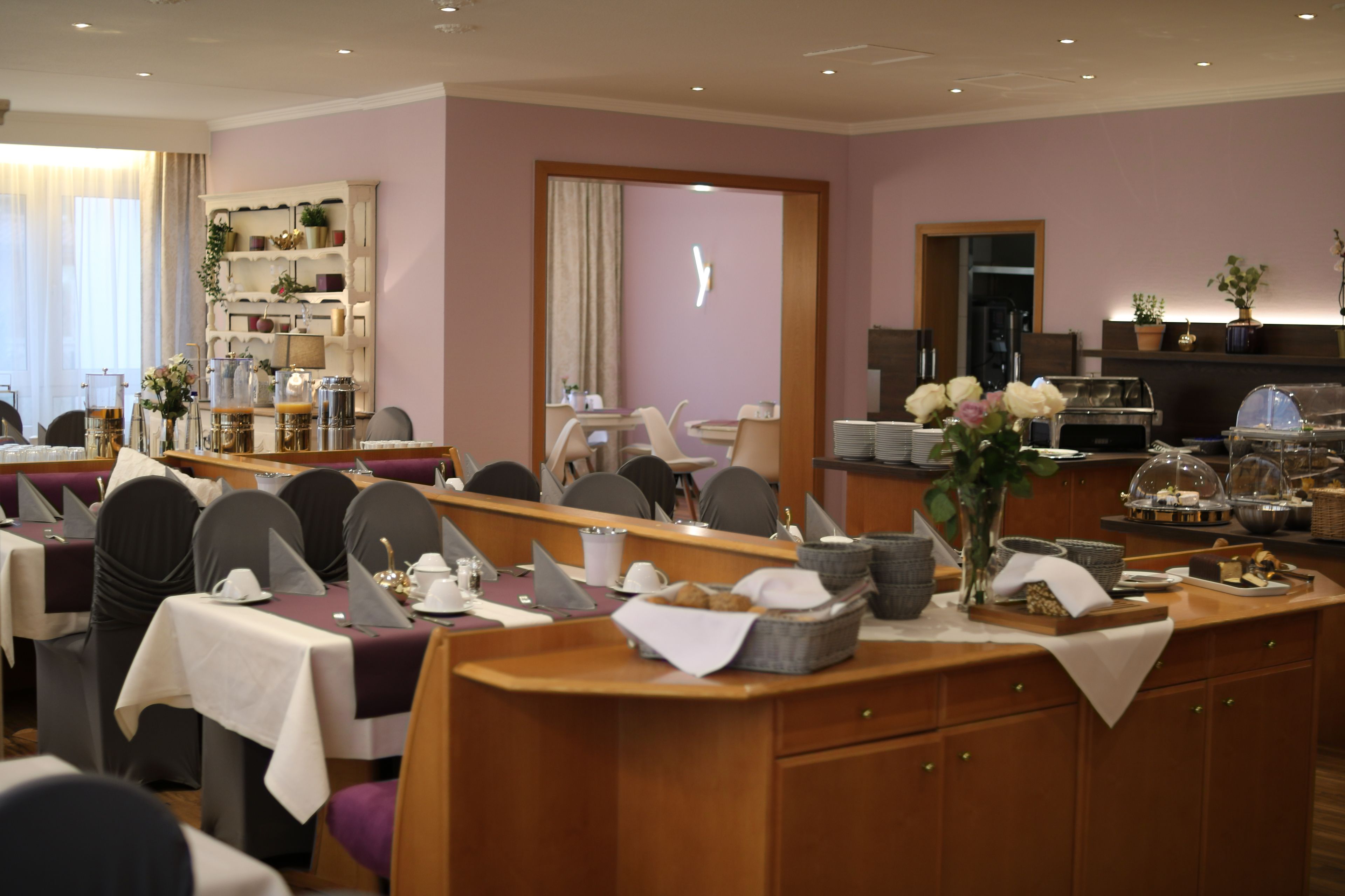 Un espace repas avec des tables dressées pour le service, un buffet et un comptoir d’accueil.