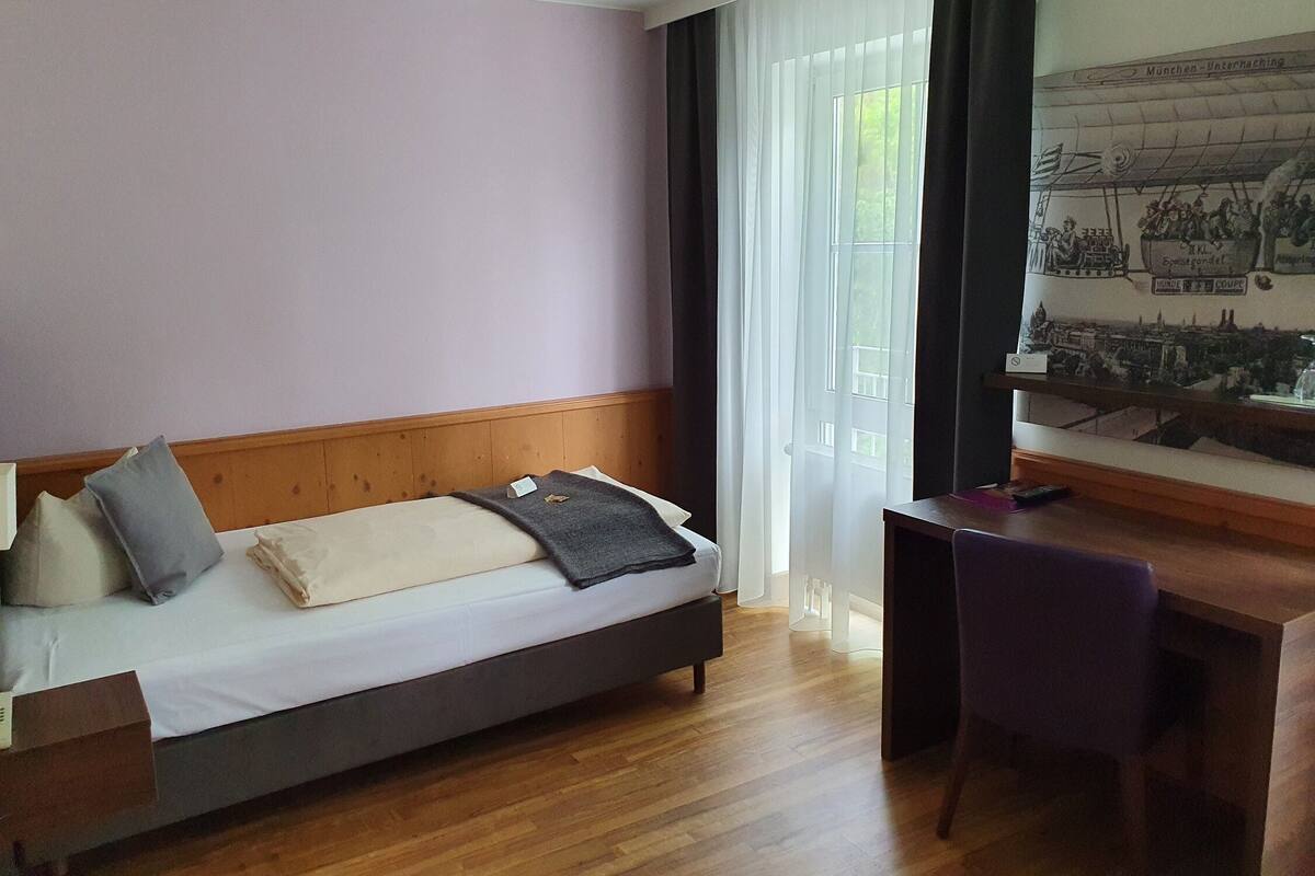 Een hotelkamer met een bed, een bureau en een raam met gordijnen.