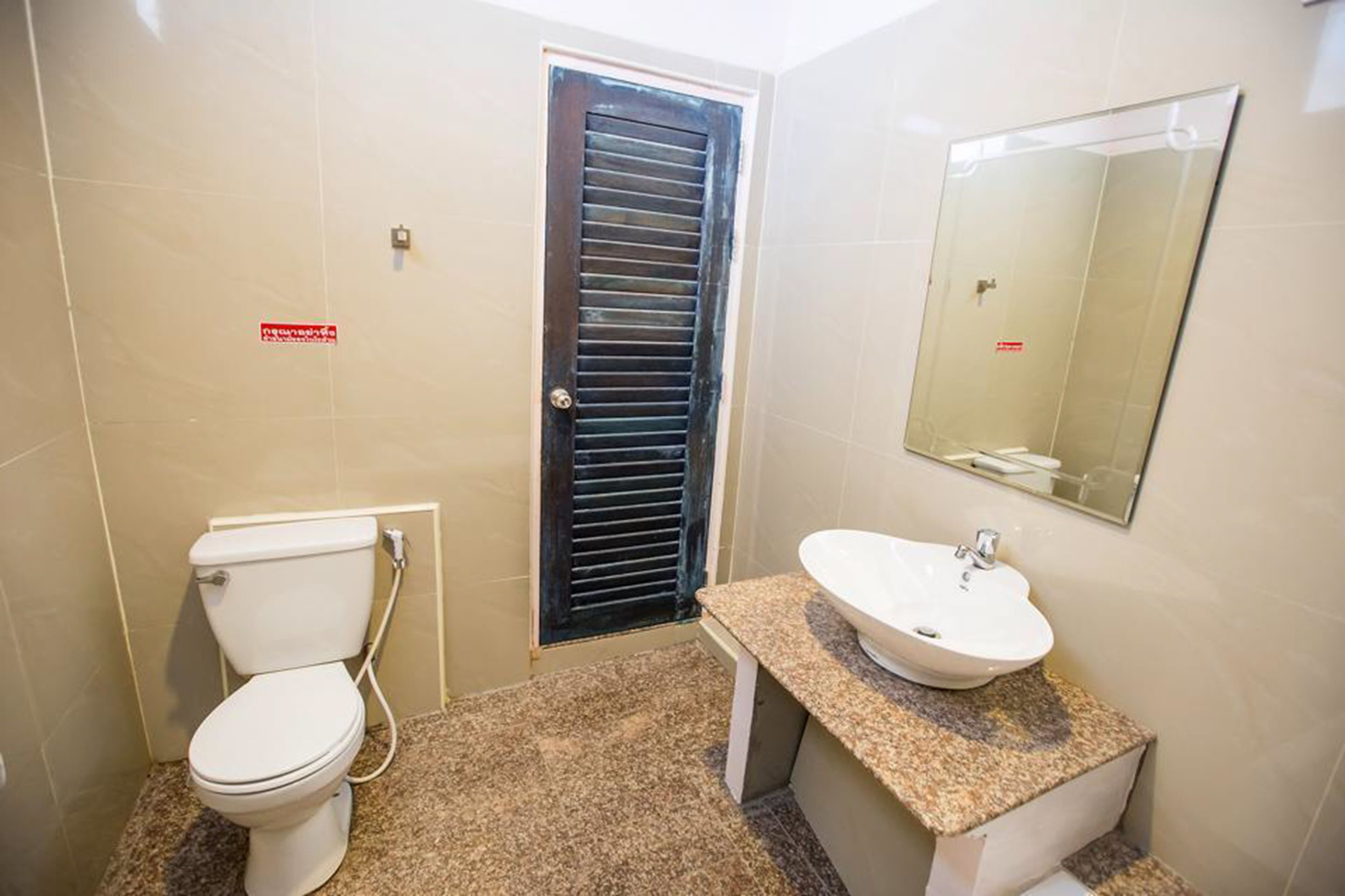A small bathroom with a toilet, sink, and mirror.