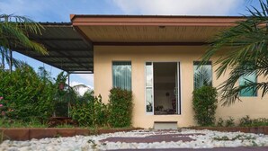 A modern house with a covered porch, surrounded by lush greenery and a gravel pathway. - Huasai Palm Inn (Hua Sai)