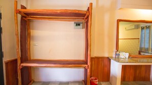 A room with a wooden bunk bed, a small trash bin, a bathroom with a sink and mirror, and a patterned wall. - Huasai Palm Inn (Hua Sai)
