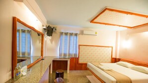 A hotel room with a bed, a wooden headboard, a mirror, a small table, and a window with curtains. - Huasai Palm Inn (Hua Sai)