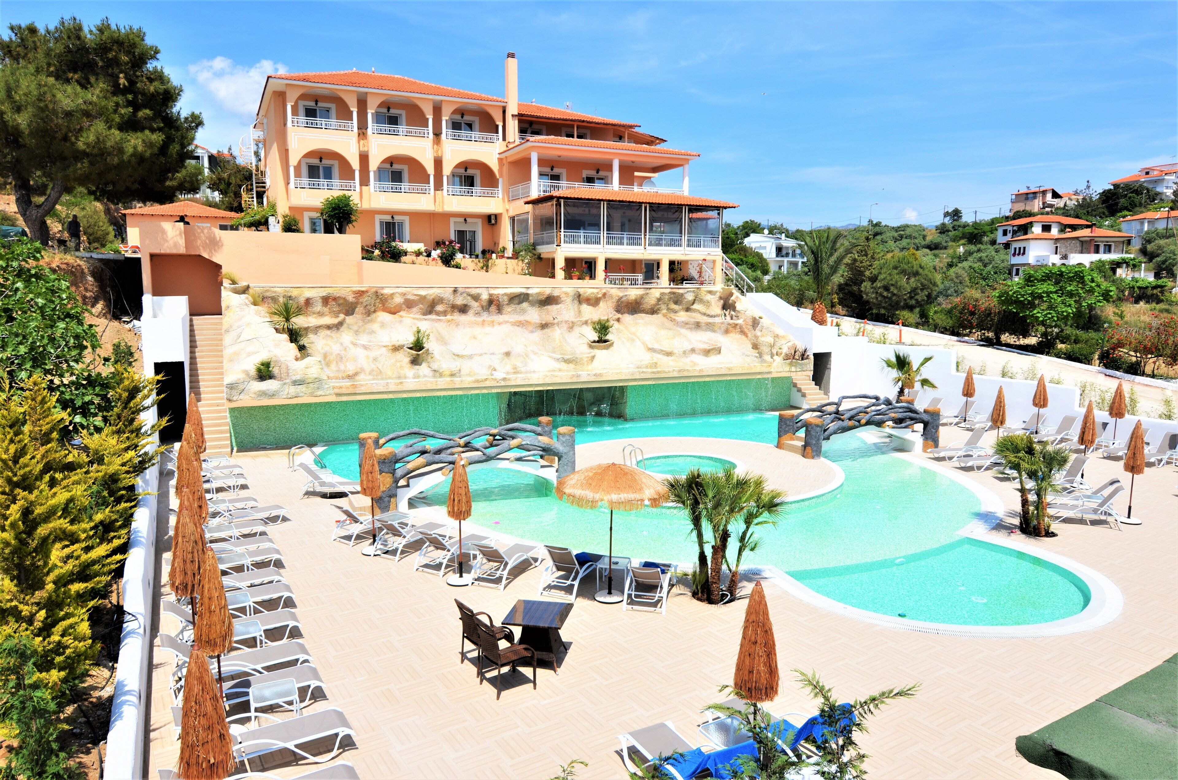 Un resort con piscina, tumbonas y un edificio con balcones.
