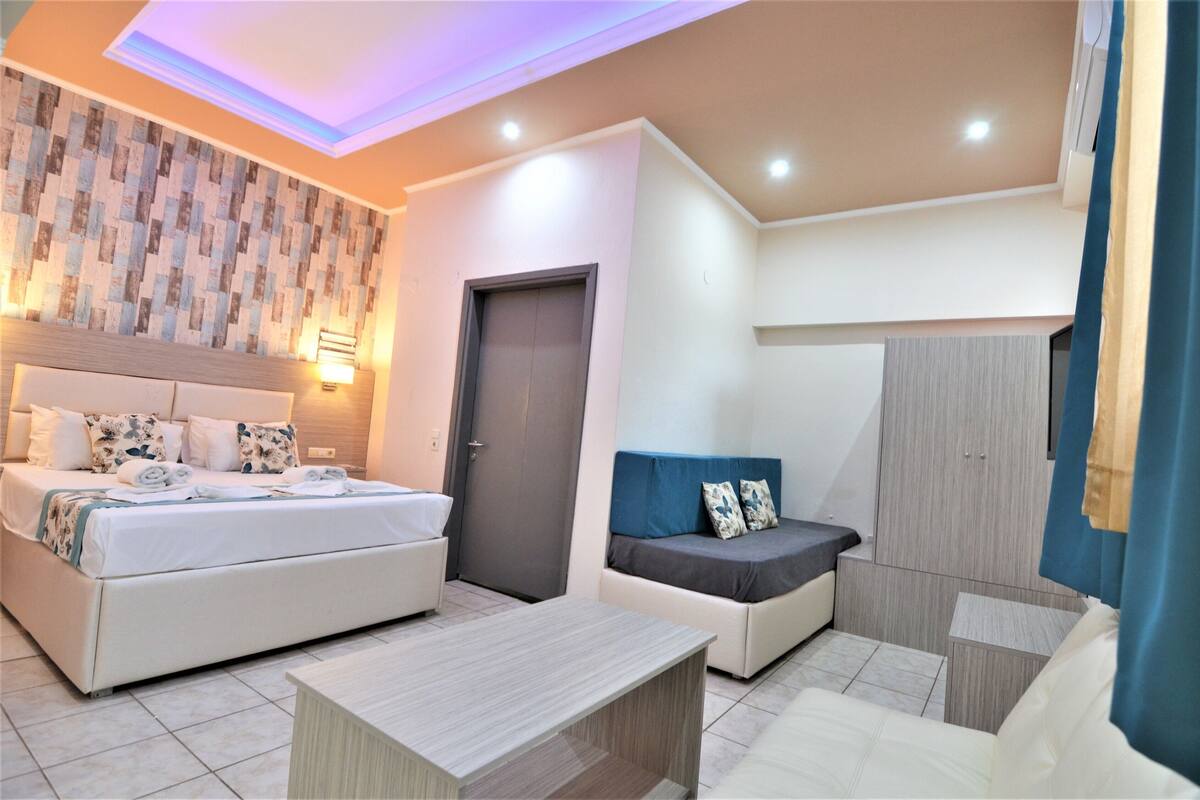 A modern hotel room with a bed, sofa, and a small table.