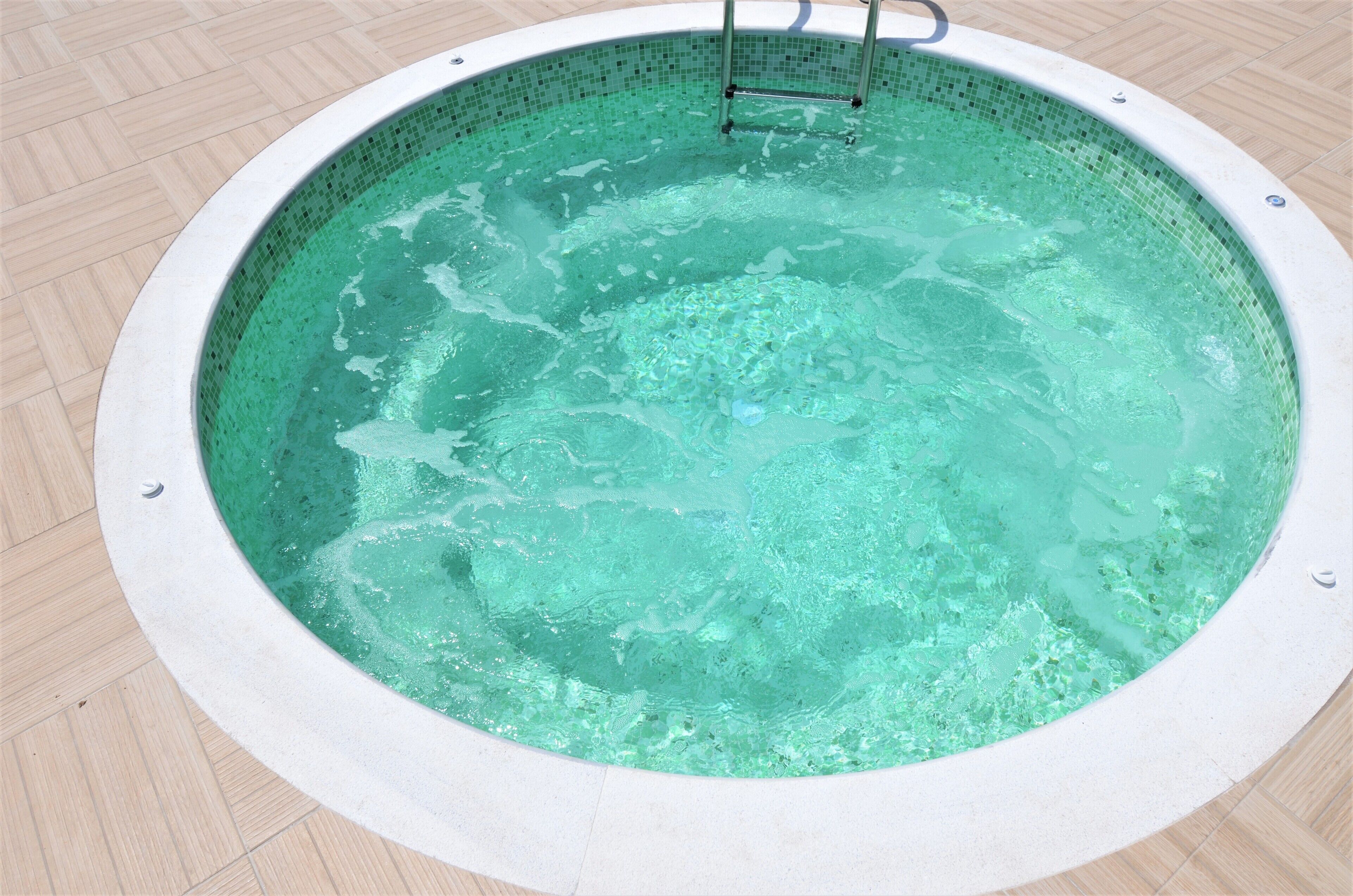 Een rond bubbelbad met betegelde binnenkant en een trap.