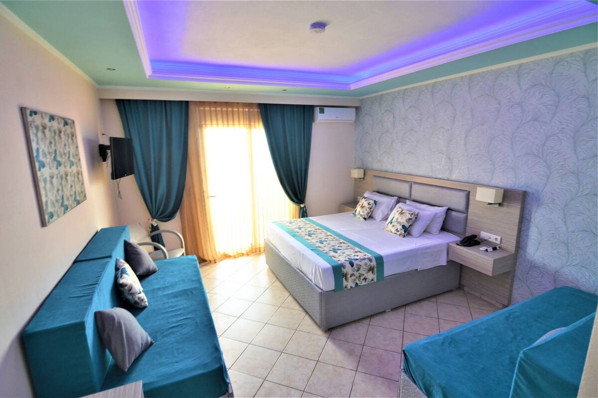 A hotel room with a bed, a bedside table, a chair, and a couch.