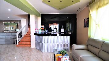 A reception area with a counter, a sofa, a coffee table, and a staircase.