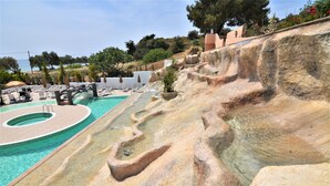 Una piscina amb un disseny original en terrasses, envoltada de gandules i ombrelles.