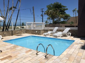 Een buitenzwembad, ligstoelen bij het zwembad