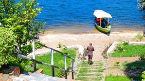 A boat docked at a beach with a person walking towards it.