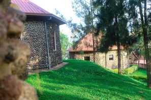 A stone building with a red roof, surrounded by a grassy area and trees.