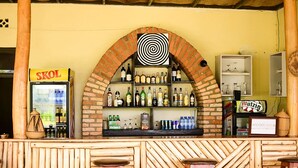 A bar with a brick archway, shelves of liquor bottles, and stools.