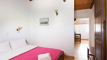 A bedroom with a bed, a wooden ceiling, a wall-mounted light, and a framed picture.