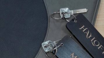 Un carnet en cuir noir avec le texte en relief « Oakwood Farm Mews » et deux porte-clés en métal portant les inscriptions « HAYLOFT » et « MEWSI ».