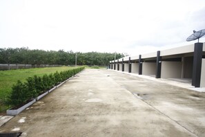 A concrete pathway leading to a building with multiple satellite dishes on the roof. - Kuakaew Garden Hotel (Nakhon Si Thammarat)