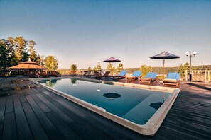 Una piscina al aire libre, sombrillas, tumbonas