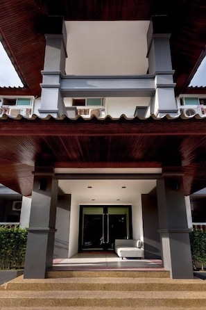 A modern building with a covered entrance, steps leading up to a door, and a bench outside. - Future Place Mansion Ubon (Ubon Ratchathani)