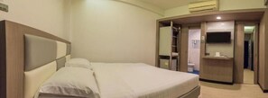 Une chambre d’hôtel équipée d’un lit, d’une télévision, d’un bureau et d’une armoire.