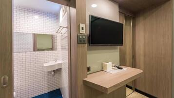 A modern bathroom with a sink, mirror, and a flat-screen TV mounted on the wall.