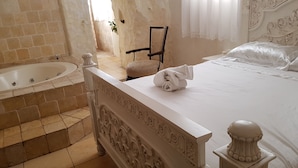 A bedroom with a large bed, a bathtub, and a chair. - Lake Mansion (Tiberias)