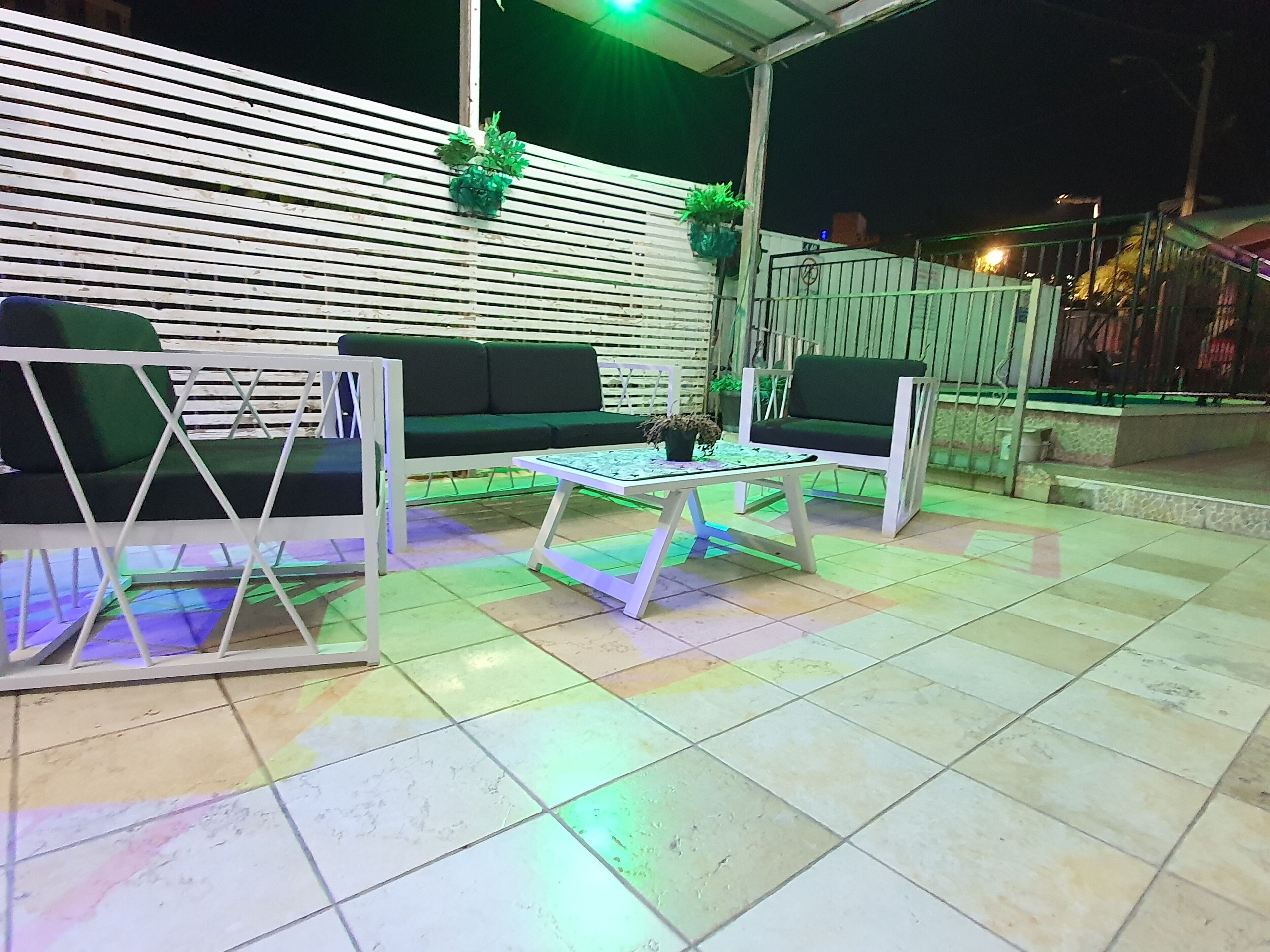 Un espace extérieur aménagé avec deux canapés et deux fauteuils, une petite table et un sol carrelé.