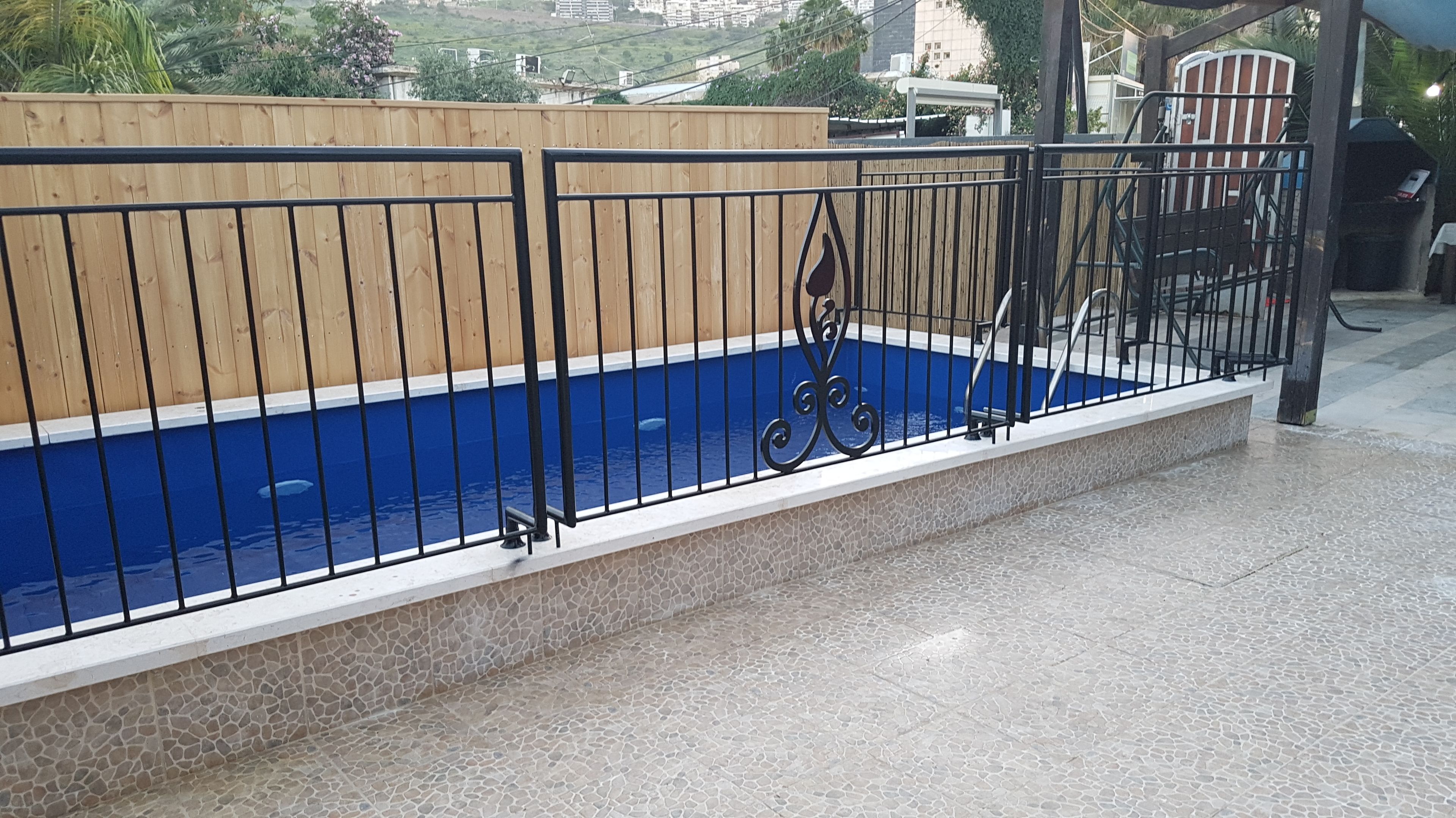 Una piscina con un borde de baldosas y valla de madera.