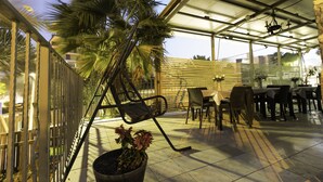 An outdoor patio with a dining area, including tables and chairs, and a potted plant. - Lake Mansion (Tiberias)