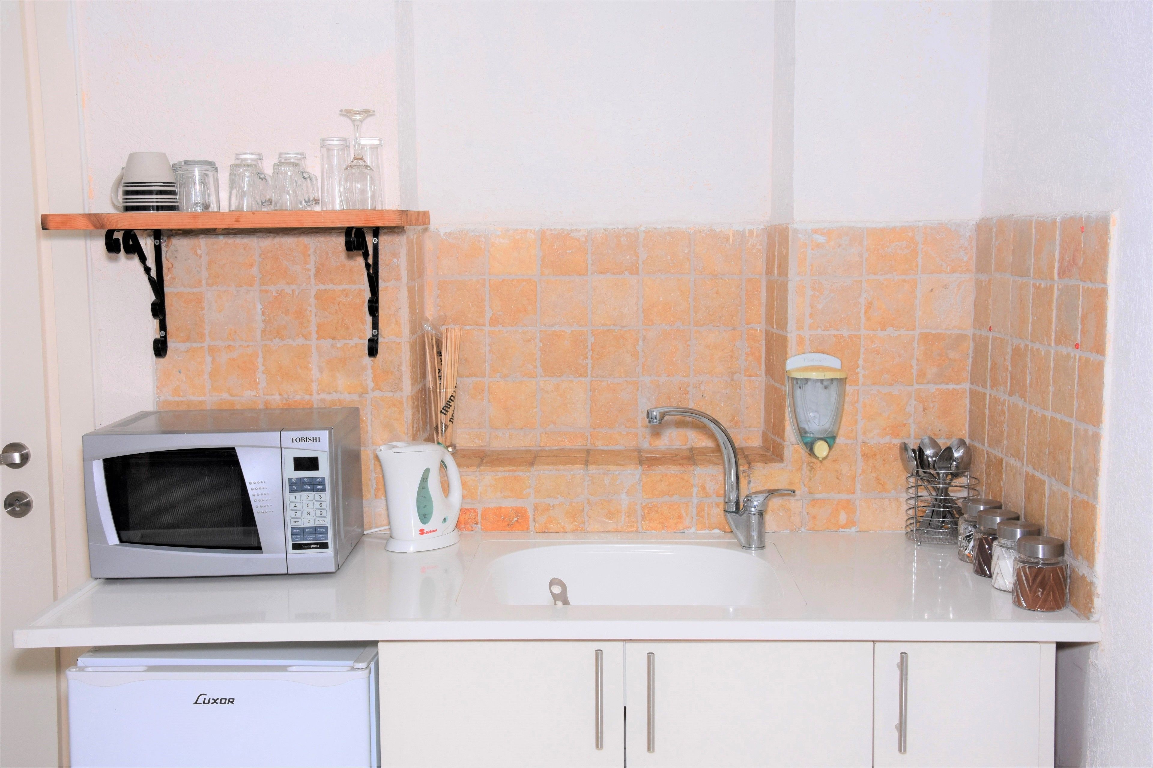 Uma cozinha com micro-ondas, pia e armários.