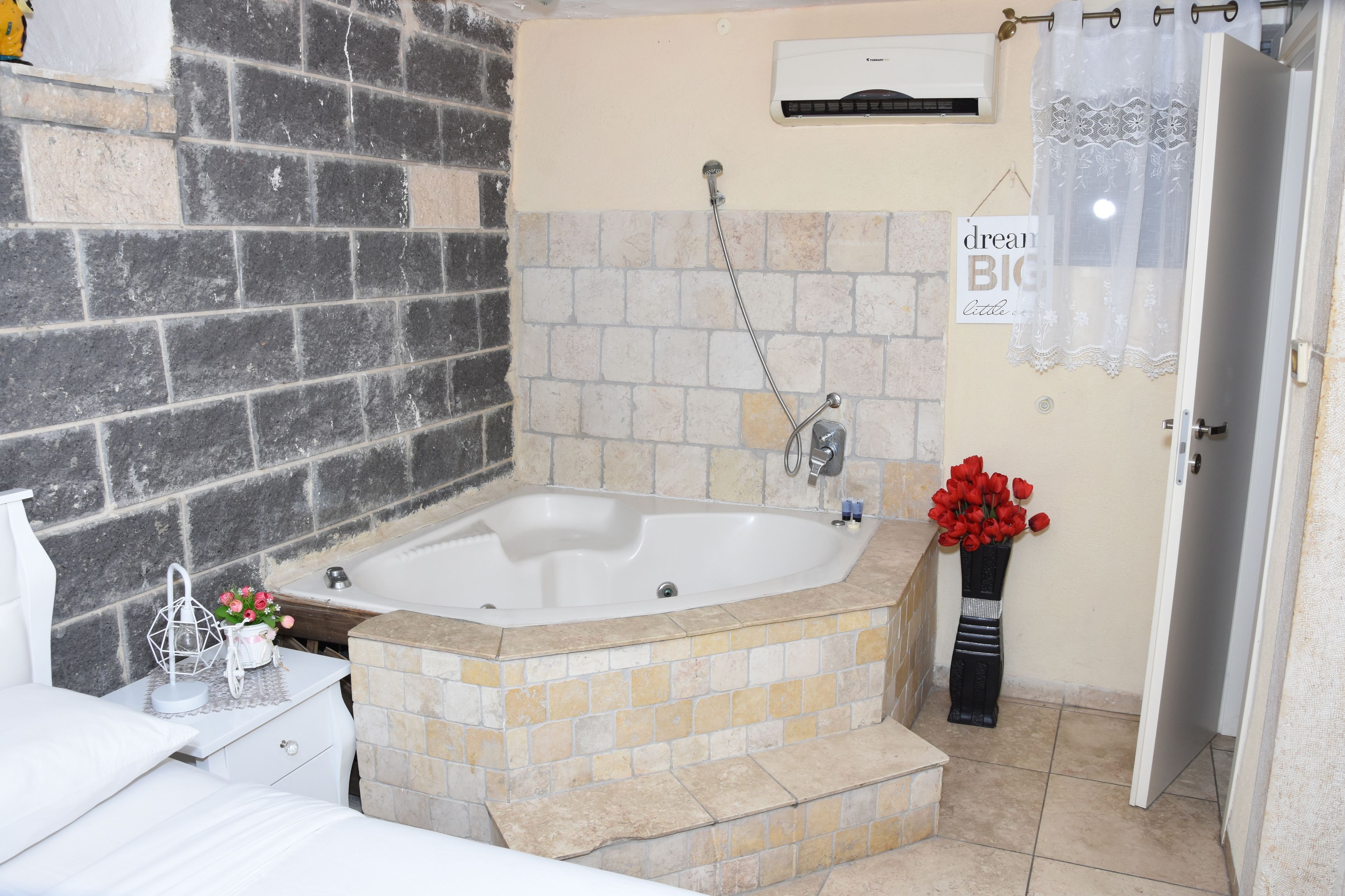 Ein Badezimmer mit Badewanne, Dusche, Waschbecken und Toilette. Ein Handtuchhalter und eine Vase mit Blumen sind vorhanden.