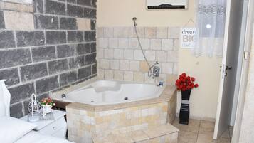 Ein Badezimmer mit Badewanne, Dusche, Waschbecken und Toilette. Ein Handtuchhalter und eine Vase mit Blumen sind vorhanden.
