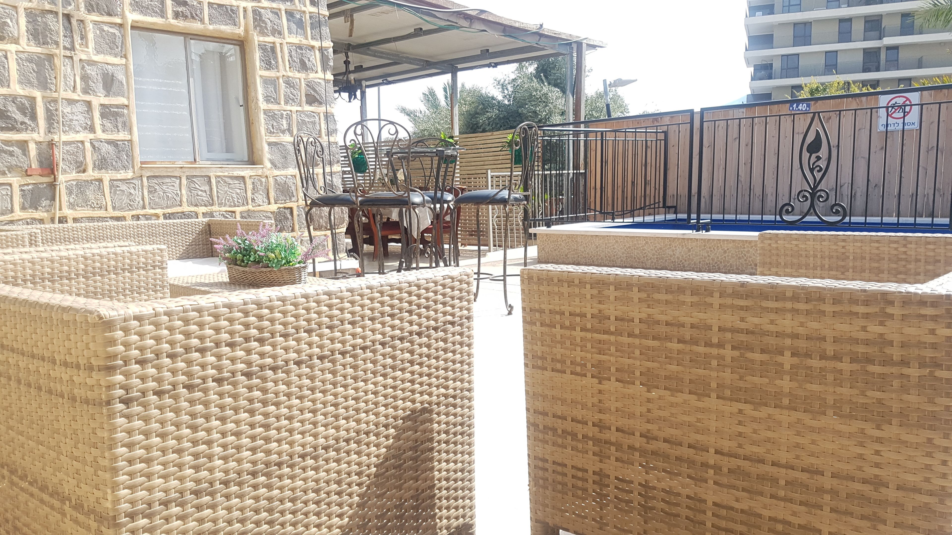 Un patio con mobiliario de mimbre, una piscina y un edificio de piedra al fondo.
