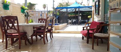 Un patio con mesa y sillas, una sombrilla azul y vistas a la calle.