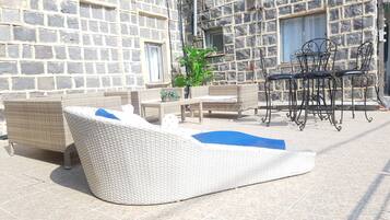 An outdoor seating area with wicker furniture, a small table, and a potted plant.