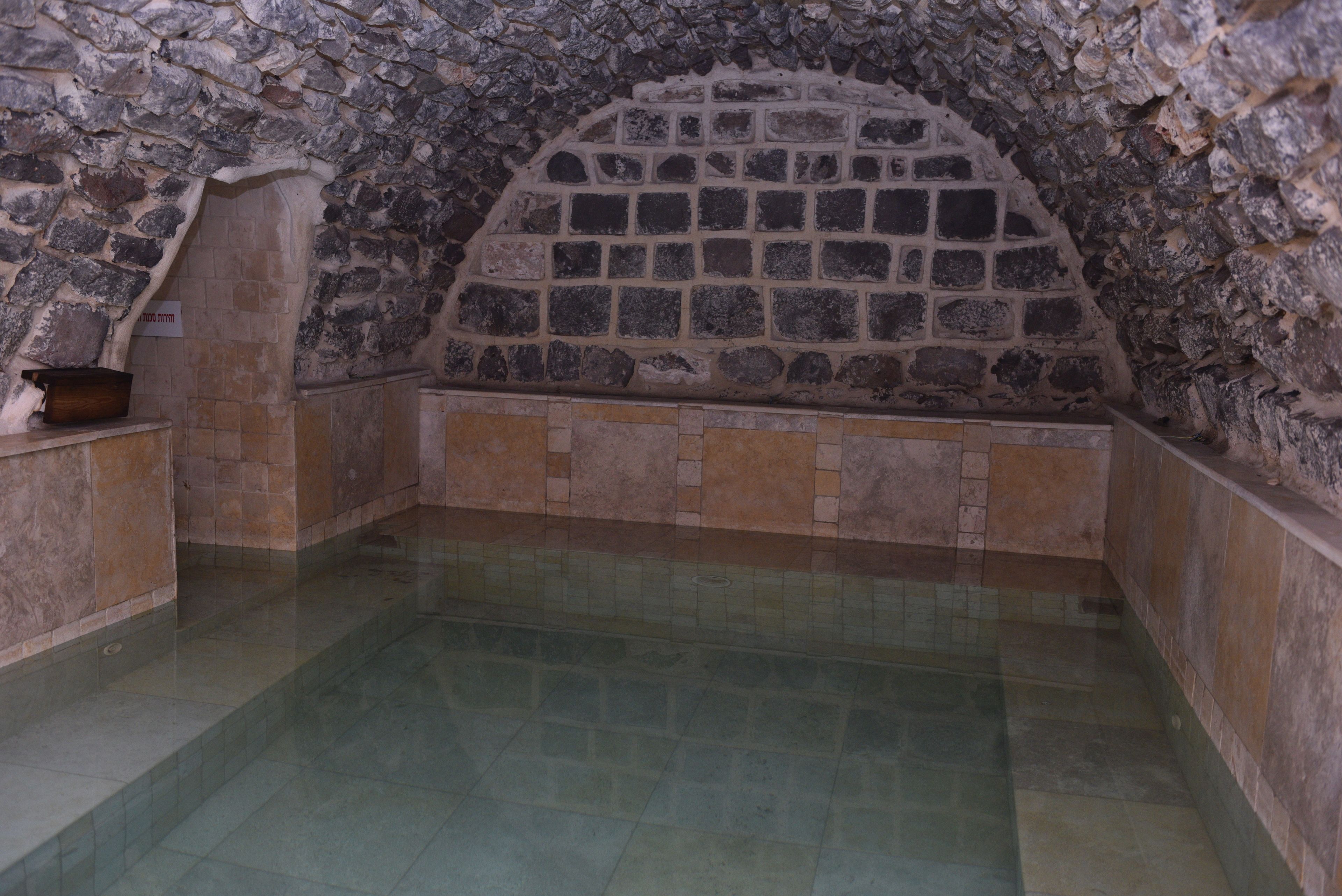 A stone-walled room with a tiled floor and a bench along the wall.