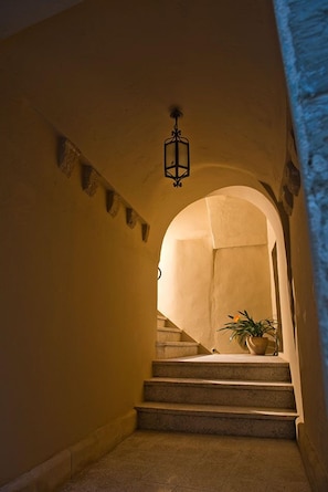 A staircase with a lantern, a potted plant, and a stone wall. - B&B Centro Storico (Otranto)
