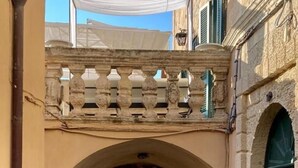 A narrow stone pathway leading through an arched doorway, flanked by buildings with traditional architecture and a mountain in the background. - B&B Centro Storico (Otranto)