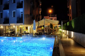 An indoor swimming pool with a tiled floor and a covered seating area with chairs and tables. - Afsin Hotel (Konyaalti)