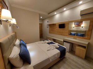 A hotel room with a bed, a desk, a mirror, and a wall-mounted TV. - Afsin Hotel (Konyaalti)