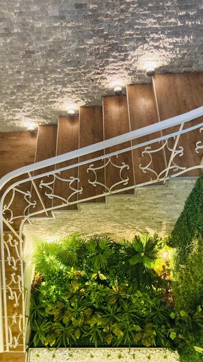 A staircase with a white metal railing, a stone wall, and a green plant wall. - Afsin Hotel (Konyaalti)