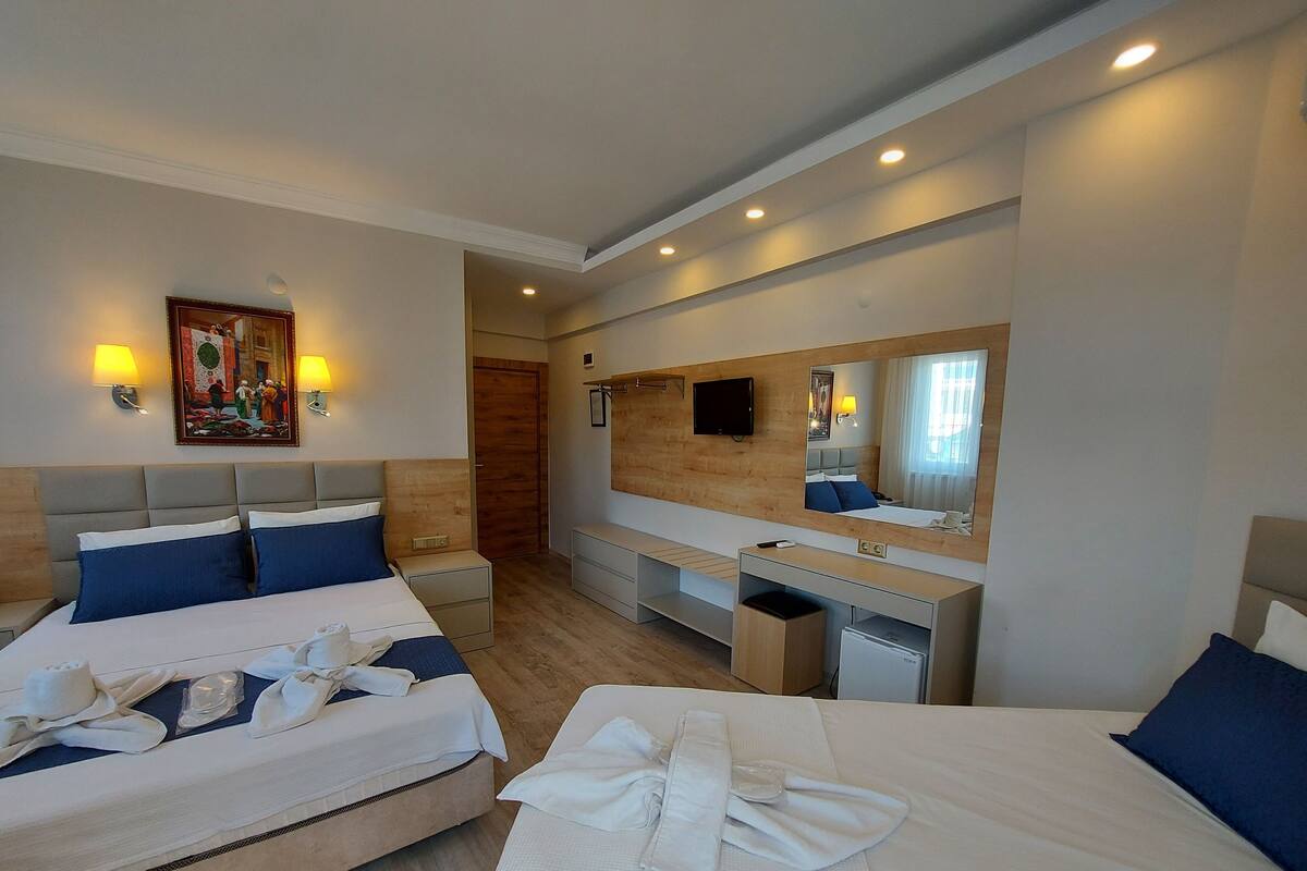 A hotel room with two beds, a desk, a mirror, and a TV.