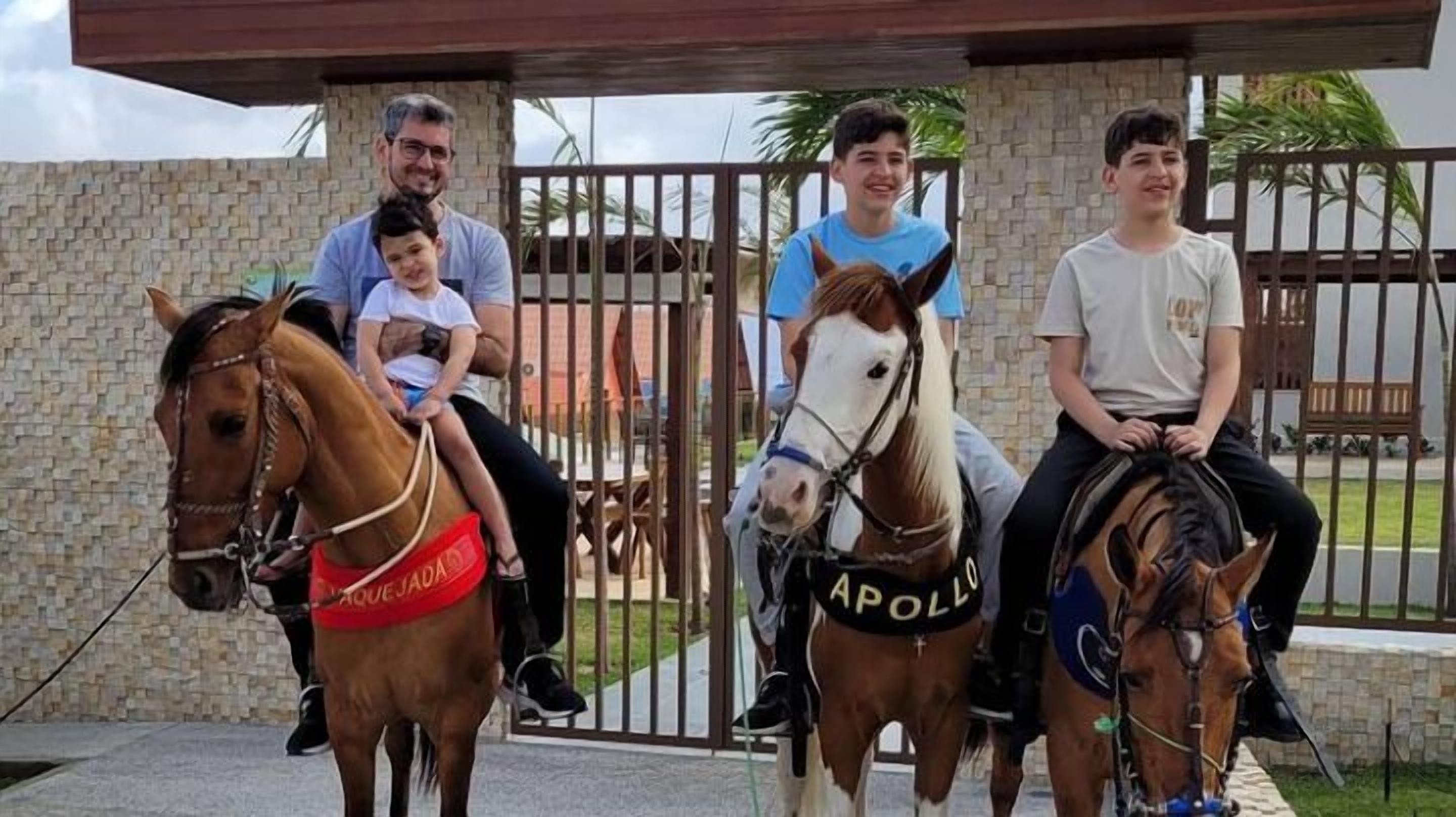 Vier personen rijden te paard in een overdekte ruimte met stenen muren en een poort.