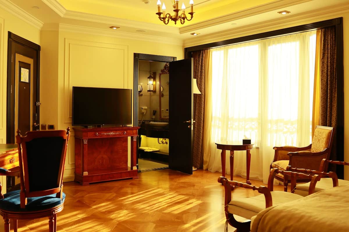 Ein Hotelzimmer mit einem großen Bett, einem Fernseher, einem Holzschrank und einer Sitzecke mit Stühlen.