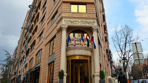 Un edificio alto y color beige con varios balcones y una entrada imponente.