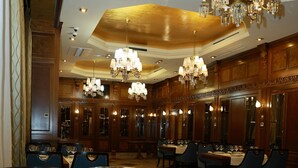 Un comedor formal con mesas dispuestas para el servicio, candelabros y paneles de madera.