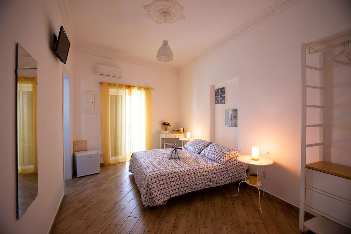 A bedroom with a bed, bedside table, lamp, and wardrobe.