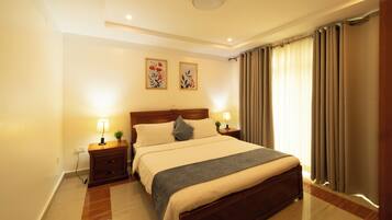 Un dormitorio con cama, mesitas de noche, lámparas y cortinas.